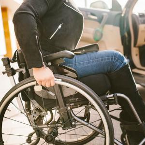 Une femme dans un fauteuil roulant près d'une voiture