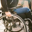 Une femme avec un handicap dans un fauteuil roulant à côté de sa voiture