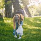 Une femme ramasse un déchet dans une forêt