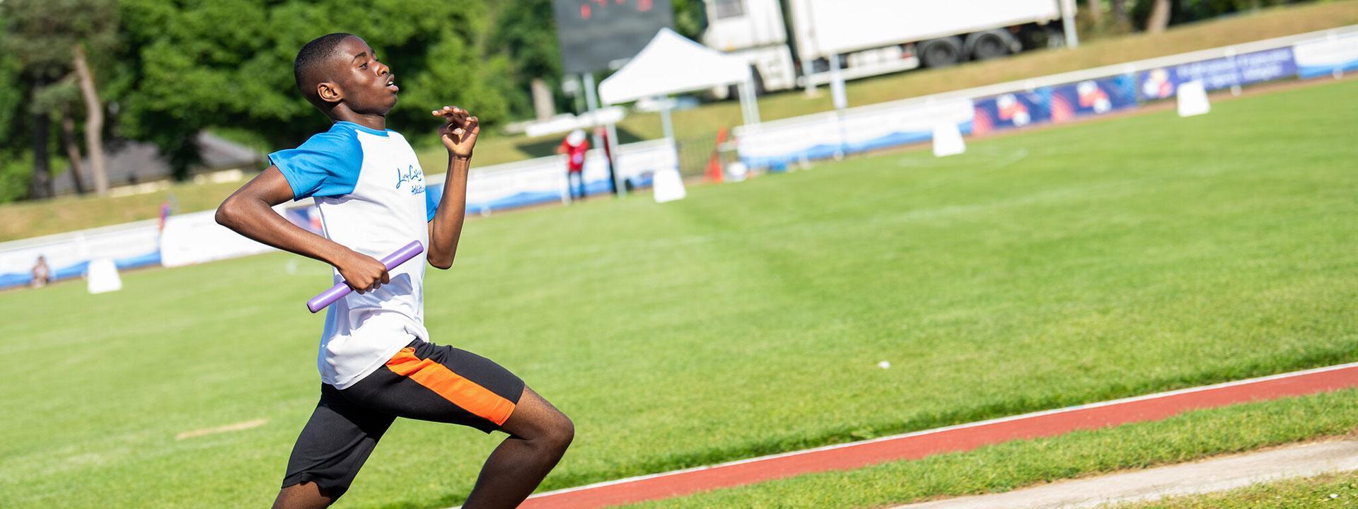 Un sportif en plein sprint dans un stade d'athlétisme