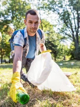 Un homme ramasse des déchets dans une forêt
