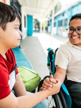 Un élève en fauteuil roulant salue un camarade de classe