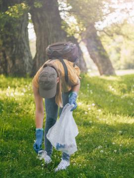 Une femme ramasse un déchet dans une forêt