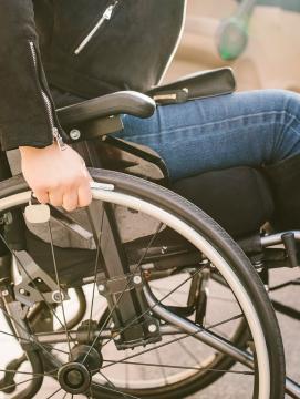 Une femme avec un handicap dans un fauteuil roulant à côté de sa voiture