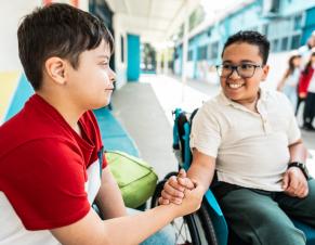 Un élève en fauteuil roulant salue un camarade de classe