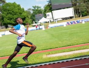 Un sportif en plein sprint dans un stade d'athlétisme