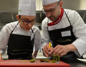 Un cuisinier montre un geste pro à une apprentie