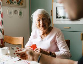 Une personne âgée joue aux cartes chez elle