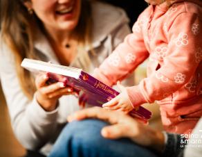 Un enfant lit un livre avec un parent