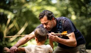 Un médiateur apprend à un enfant à tirer comme les hommes préhistoriques