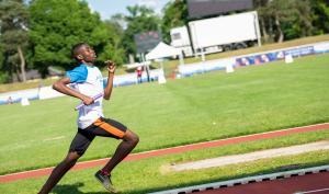 Un sportif en plein sprint dans un stade d'athlétisme