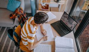 Un adolescent faisant ses devoirs devant son ordinateur dans sa chambre