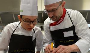 Un cuisinier montre un geste pro à une apprentie