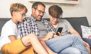 un père de famille avec ses deux garçons et son smartphone