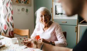 Une personne âgée joue aux cartes chez elle