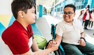 Un élève en fauteuil roulant salue un camarade de classe