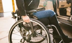 Une femme avec un handicap dans un fauteuil roulant à côté de sa voiture