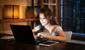 Une jeune femme devant son ordinateur le soir