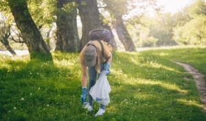 Une femme ramasse un déchet dans une forêt