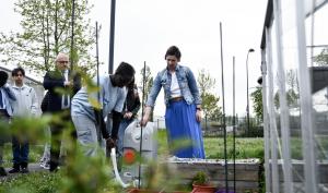 Un collégien arrose un potager à l'aide d'un récupérateur d'eau