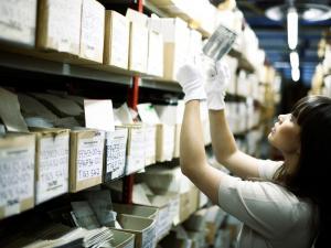 une femme observe une photographie dans un fonds d'archives