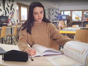 Une collégienne fait ses devoirs en classe