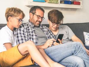 un père de famille avec ses deux garçons et son smartphone