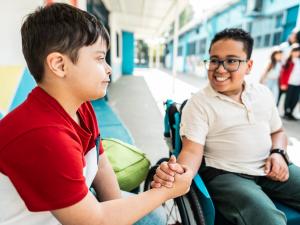 Un élève en fauteuil roulant salue un camarade de classe