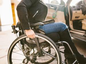 Une femme dans un fauteuil roulant près d'une voiture