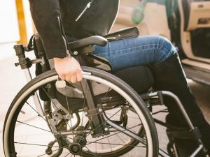 Une femme avec un handicap dans un fauteuil roulant à côté de sa voiture