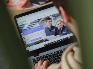 Une personne devant son ordinateur cherchant un emploi sur job77