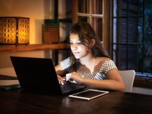 Une jeune femme devant son ordinateur le soir