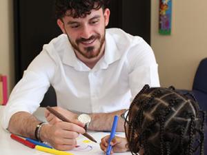 Hugo Issaly, référent de l'aide sociale à l'enfance, dessine avec une petite fille