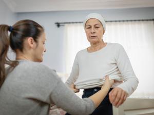 Un proche aidant habille une personne âgée