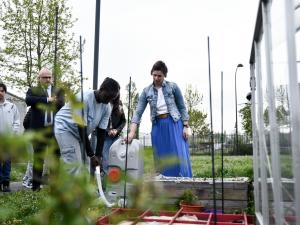 Un collégien arrose un potager à l'aide d'un récupérateur d'eau