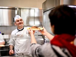Un cuisinier sert un plat à la cantine