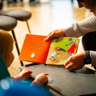 Un enfant lit un livre avec un parent