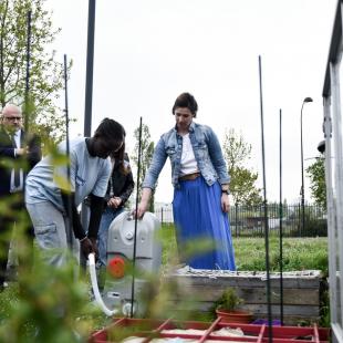 Un collégien arrose un potager à l'aide d'un récupérateur d'eau