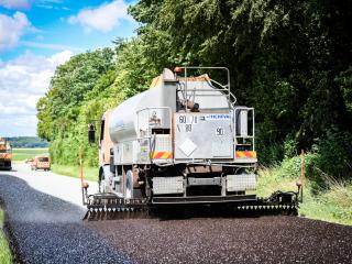 un engin pose de l'enrobée sur la chaussée