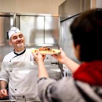 Un cuisinier sert un plat à la cantine