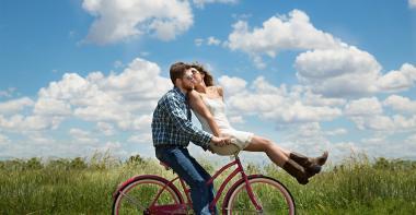 Deux jeunes sur un vélo qui s'embrassent