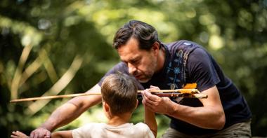 Un médiateur apprend à un enfant à tirer comme les hommes préhistoriques