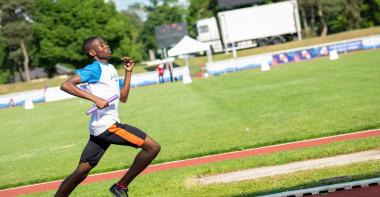 Un sportif en plein sprint dans un stade d'athlétisme