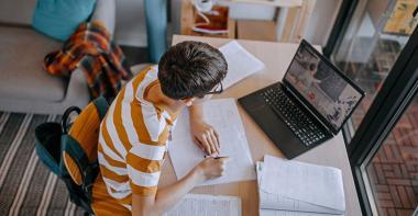 Un adolescent faisant ses devoirs devant son ordinateur dans sa chambre