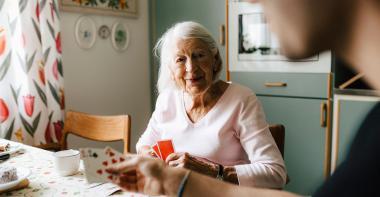 Une personne âgée joue aux cartes chez elle