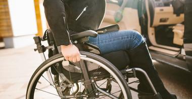 Une femme dans un fauteuil roulant près d'une voiture