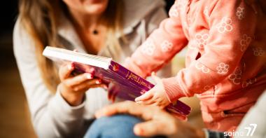Un enfant lit un livre avec un parent