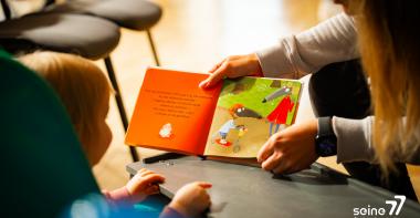 Un enfant lit un livre avec un parent