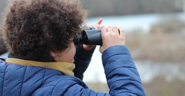 Un enfant observe la nature à travers des jumelles