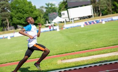 Un sportif en plein sprint dans un stade d'athlétisme